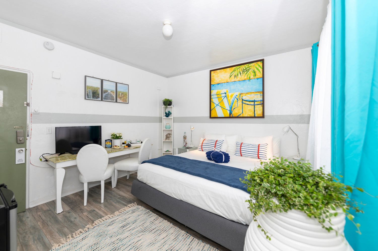 A clean and modern hotel room with a bed, desk, TV, and chair.