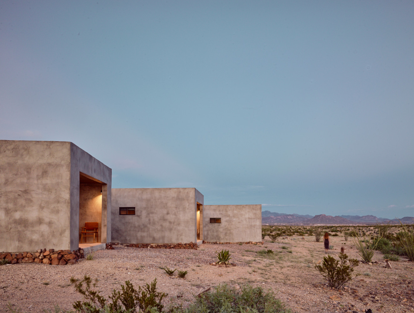 A modern, concrete building in the desert with a mountain view.