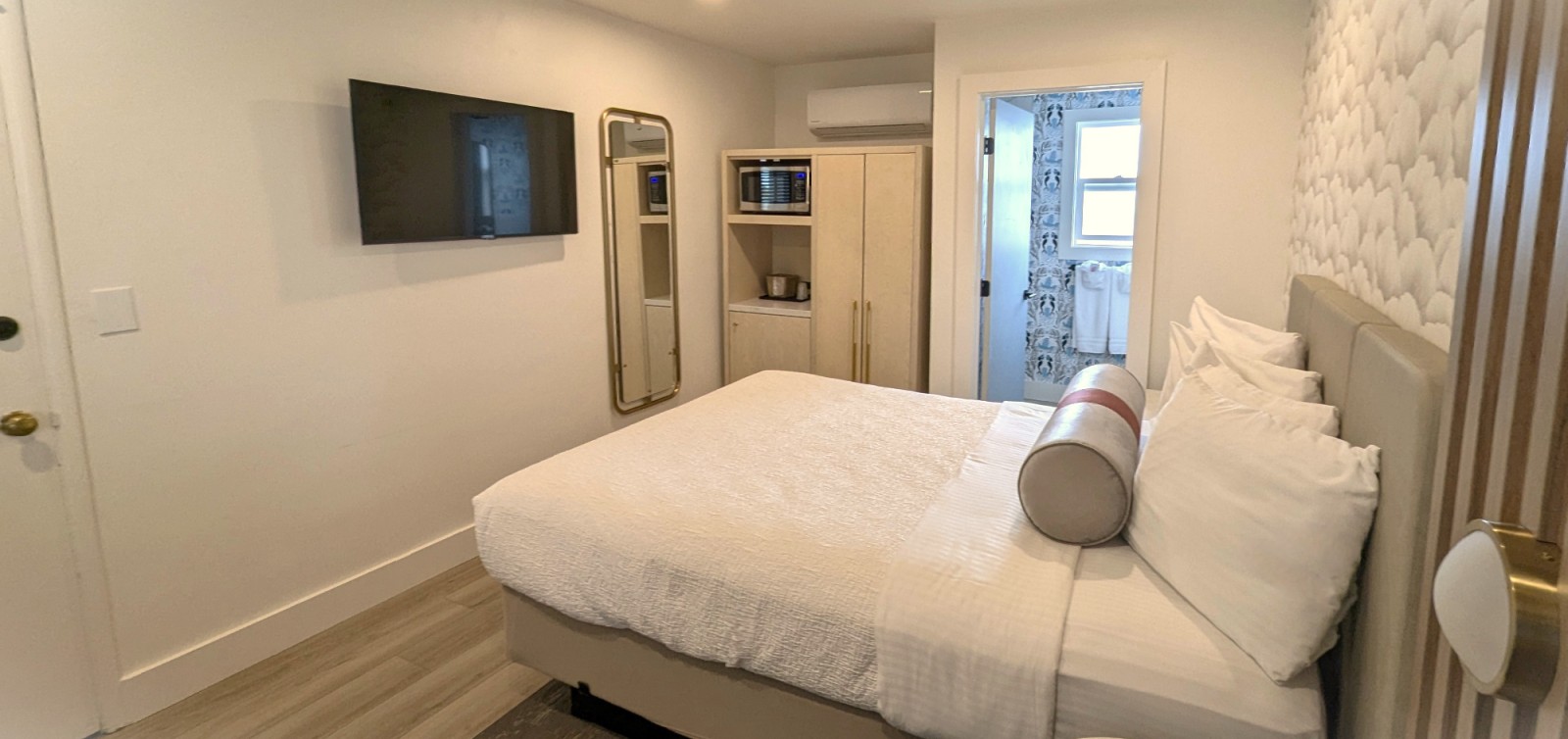 A hotel room with a bed, TV, microwave, and closet