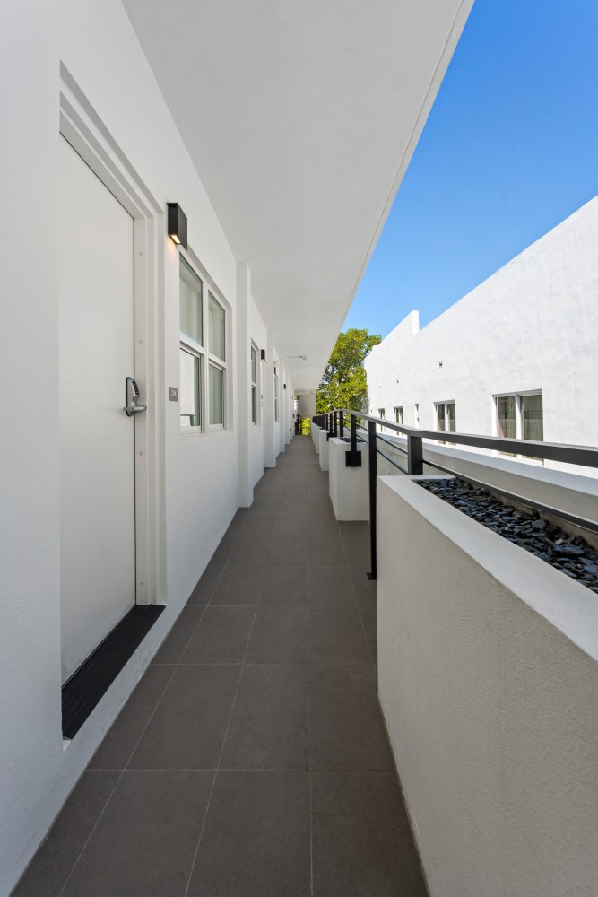 A long, white balcony with black railing and gray tiles