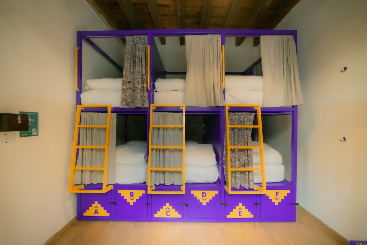 A room with a purple bunk bed with yellow ladders and white bedding
