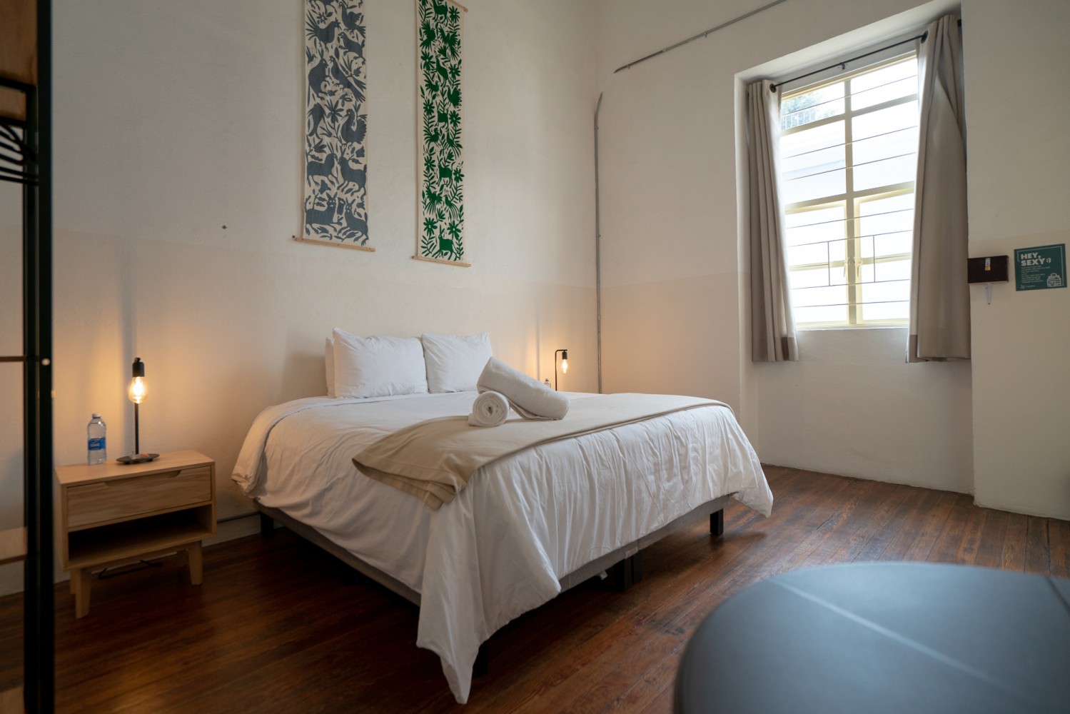 A wide view of a room with a bed, nightstand, and window