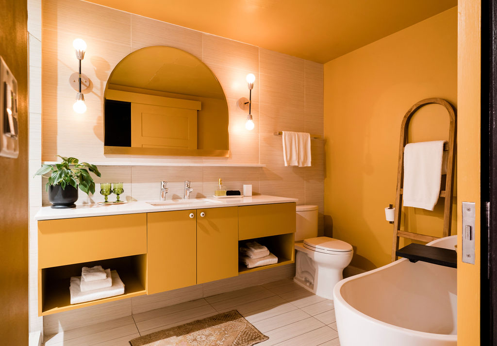 A modern bathroom with yellow walls and a white countertop