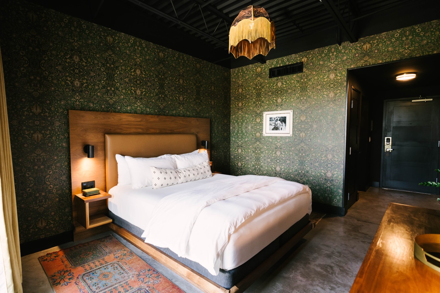 A hotel room with a large bed, nightstand, and doorway
