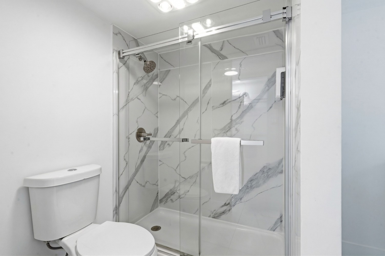 A bathroom with a toilet and a shower with a glass enclosure.