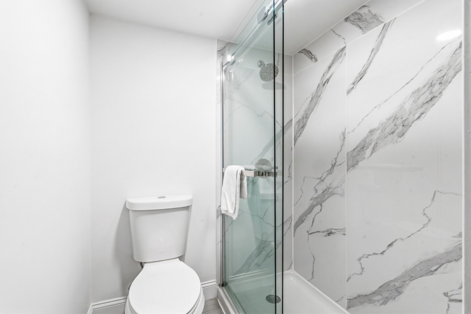 A clean and modern bathroom with a toilet and a glass-enclosed shower