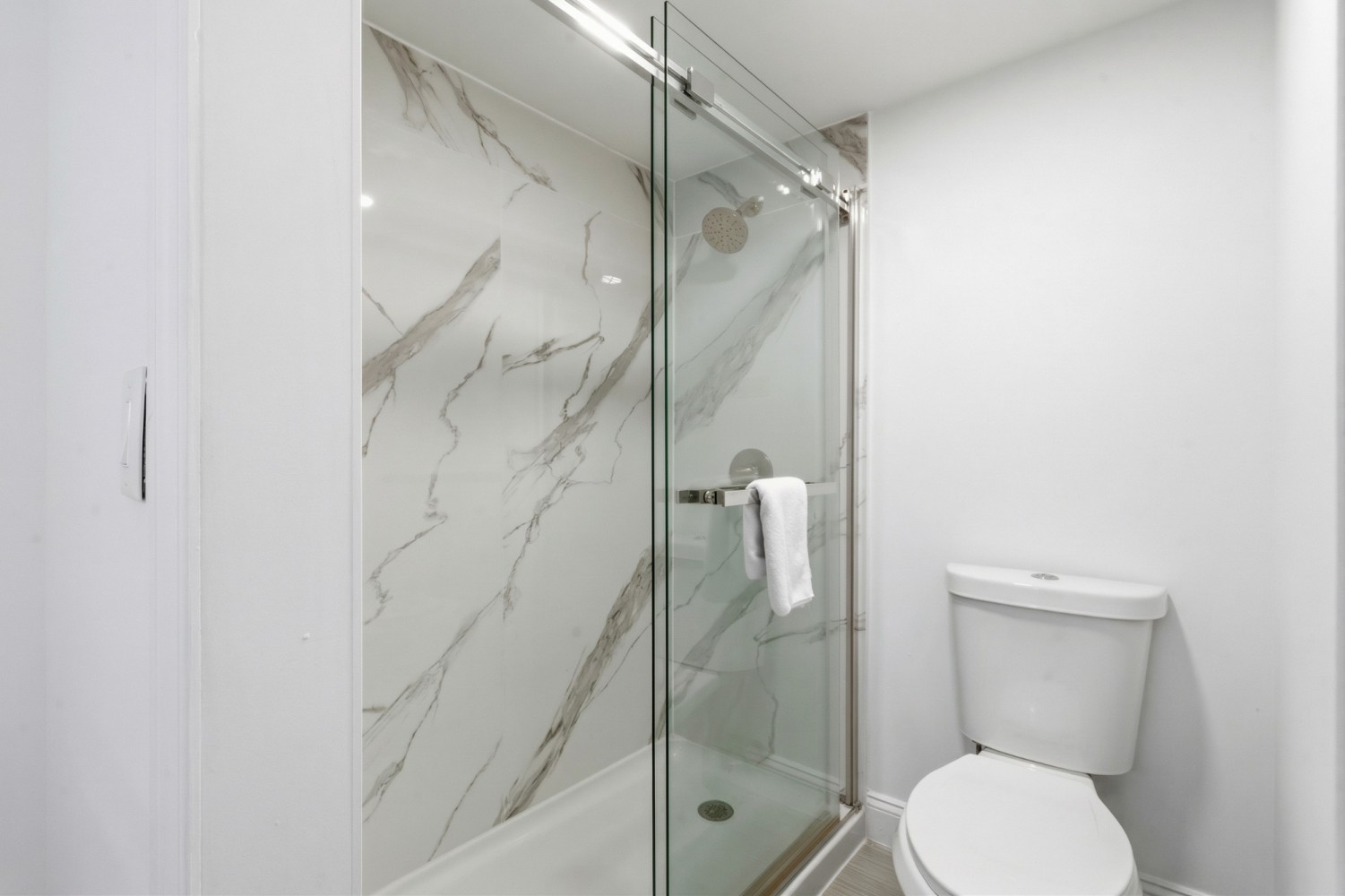 a clean bathroom with a marble shower and toilet