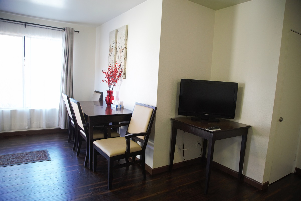 A hotel room with a dining table, TV, and window