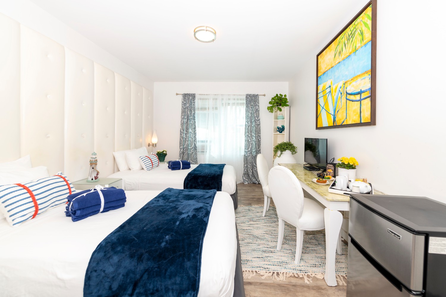 A hotel room with two beds, a desk, and a TV.