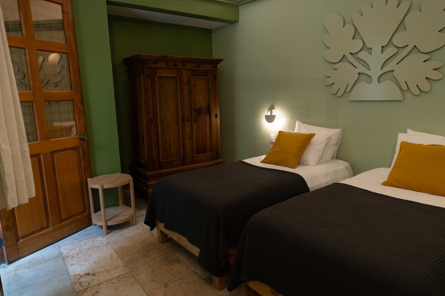 A room with two twin beds, a wooden armoire, and green walls.