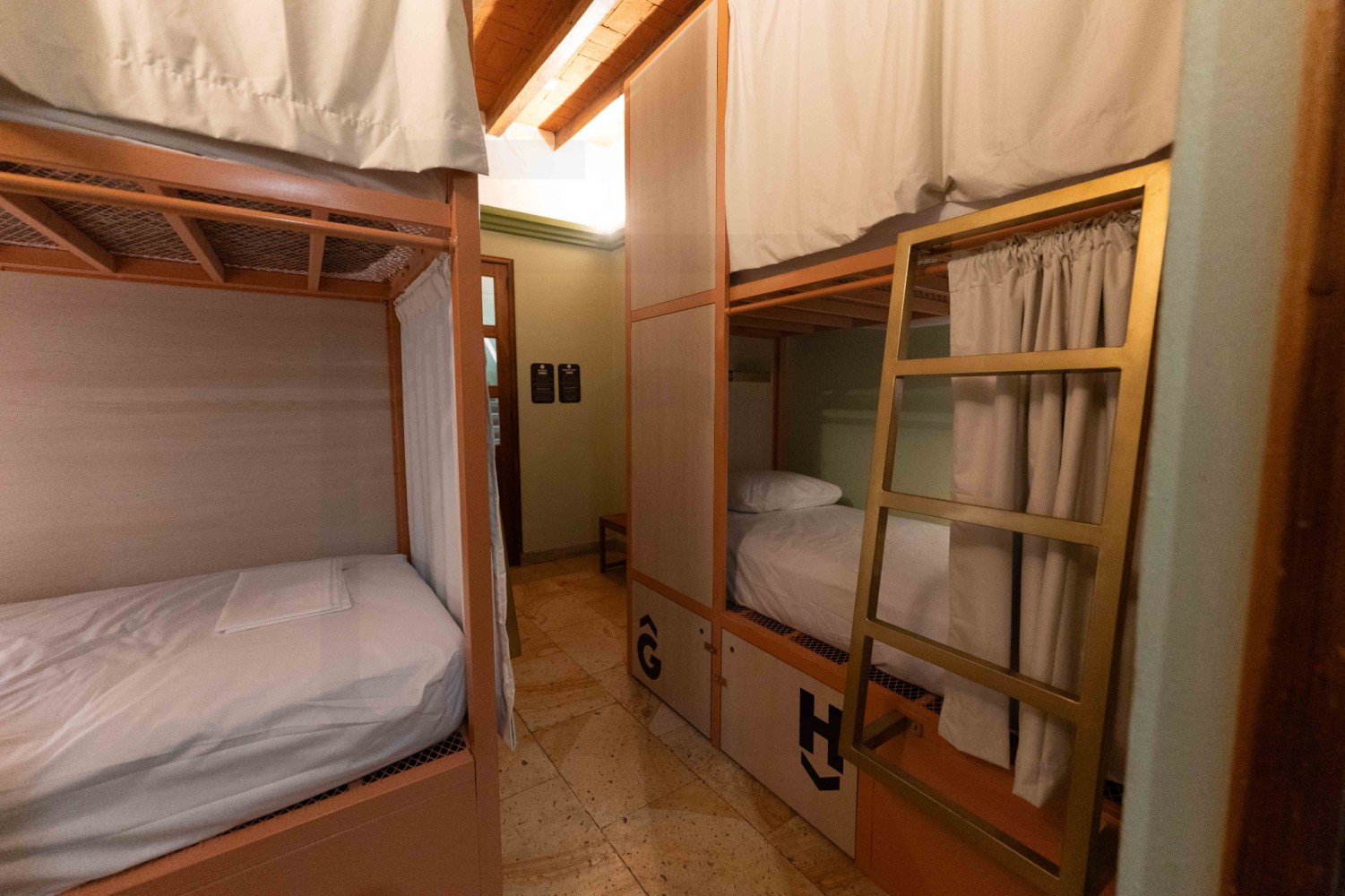 A shared room with two sets of bunk beds, white bedding, and wooden bunk frames.