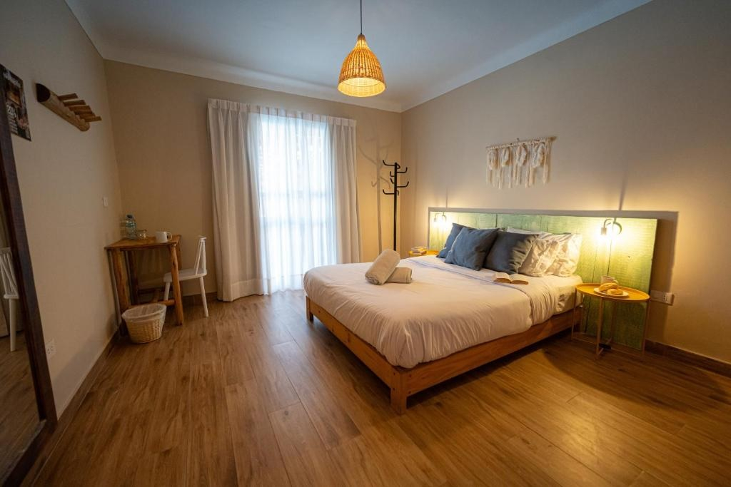 A wide view of a hotel room with a bed, nightstand, desk, and window.