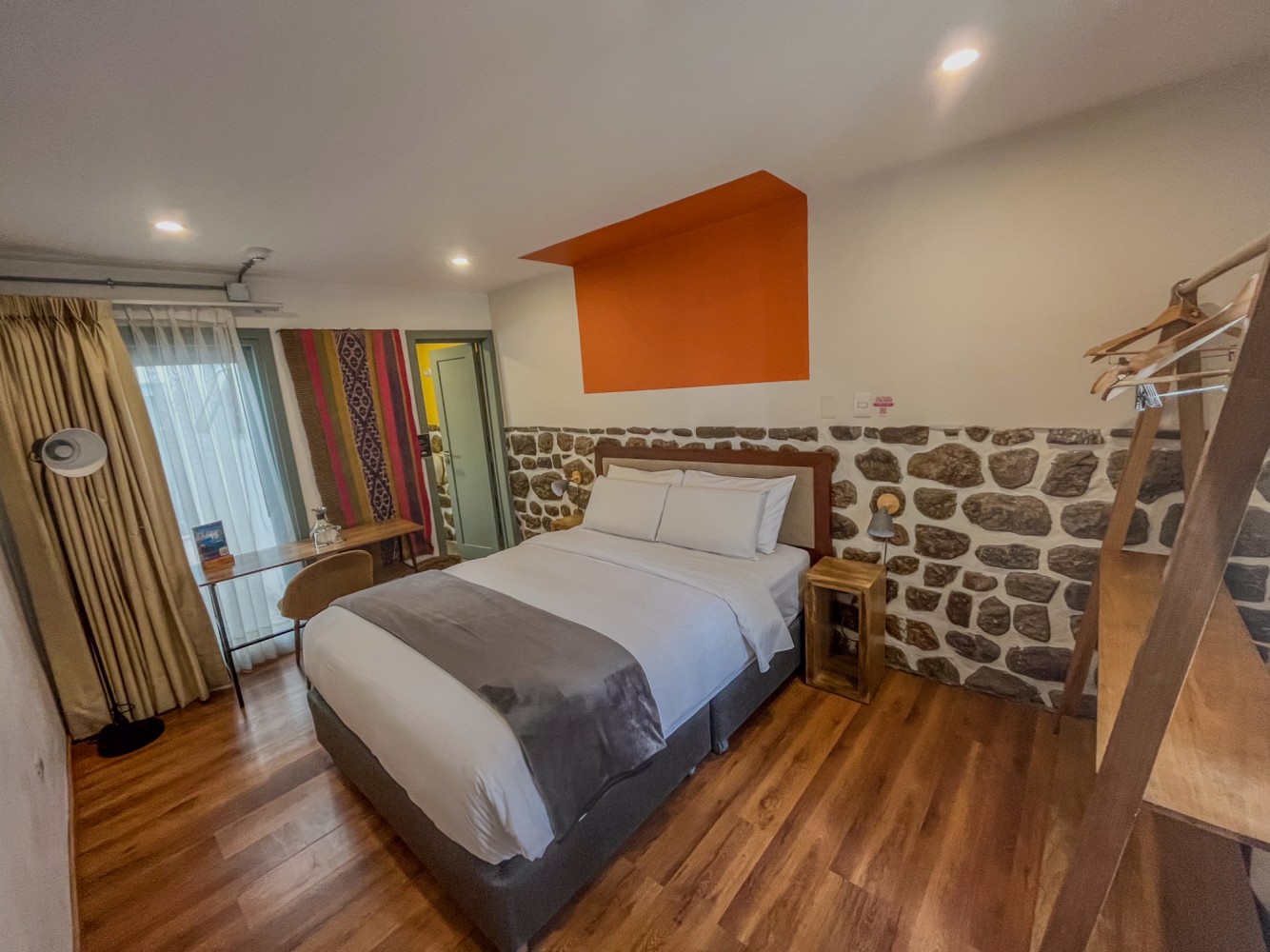 A hotel room with a bed, desk, and window